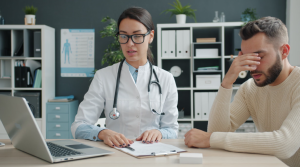 Healthcare professional discussing with patient in doctor's office. Stress and concern are evident.
